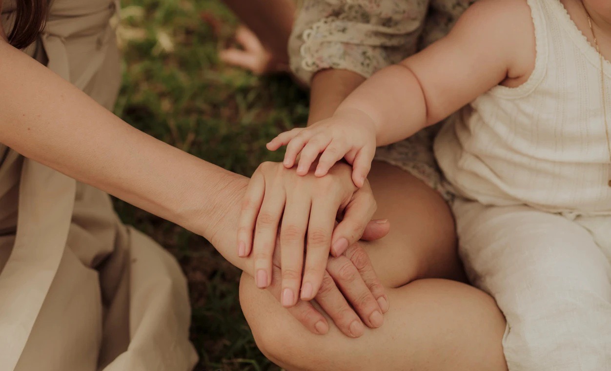 Three generations of hands resting together