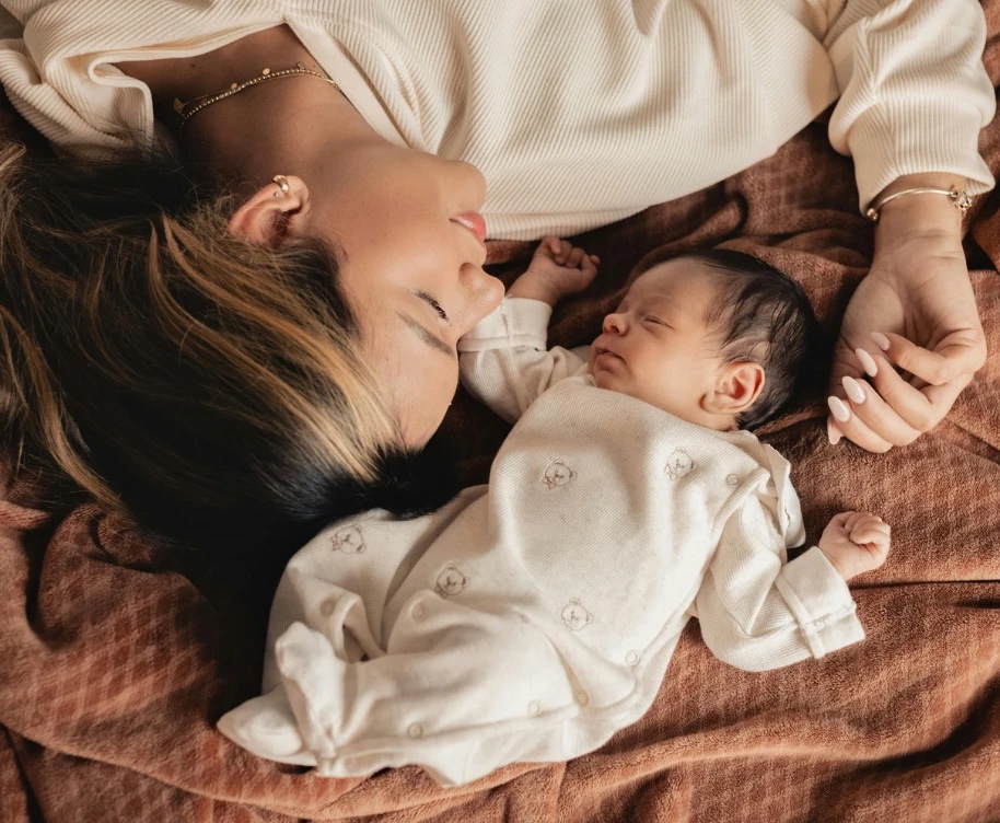 A mother lying beside her sleeping newborn baby
